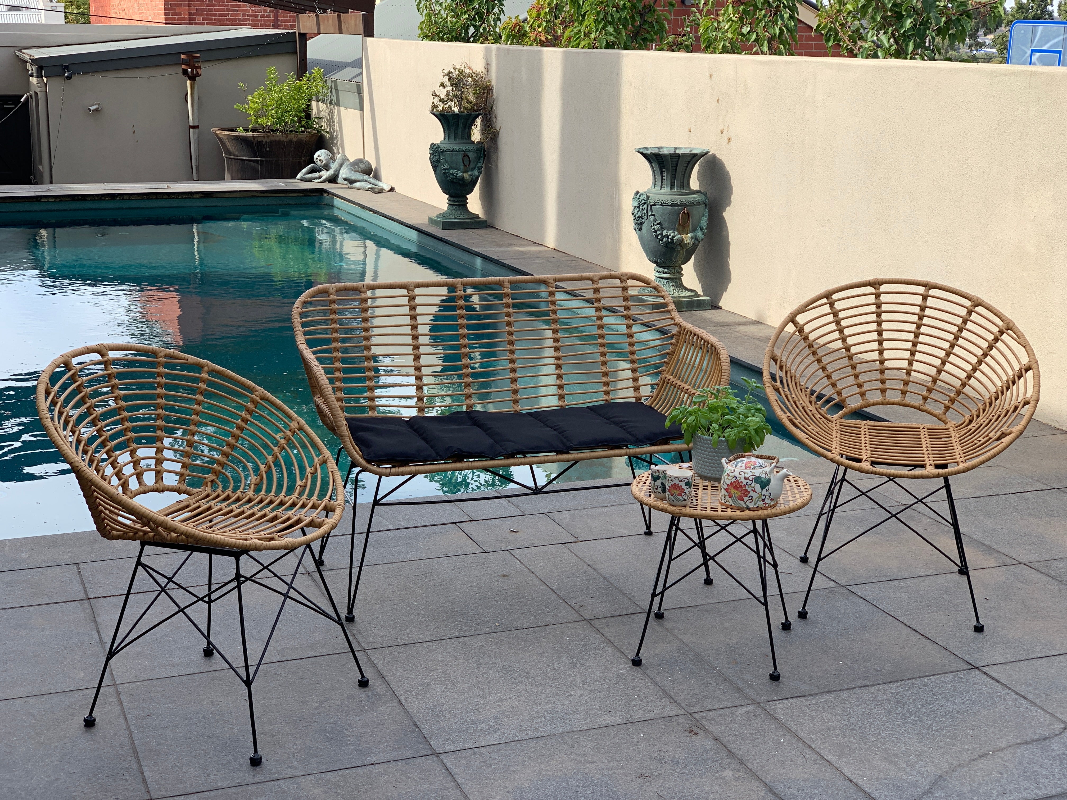 Outdoor patio setting Isla with bench seat, made from plastic/PU simulated cane, in natural cane finish. Pictured in a pool setting.