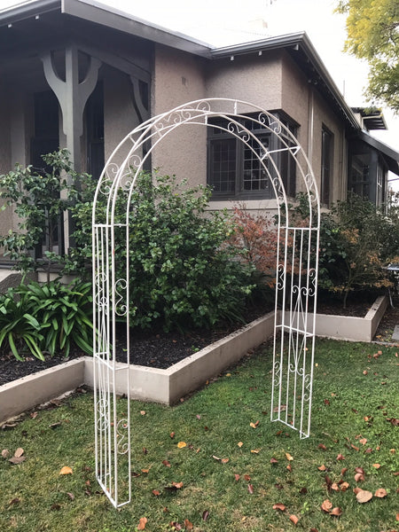Wide metal garden arch in distressed cream in garden setting